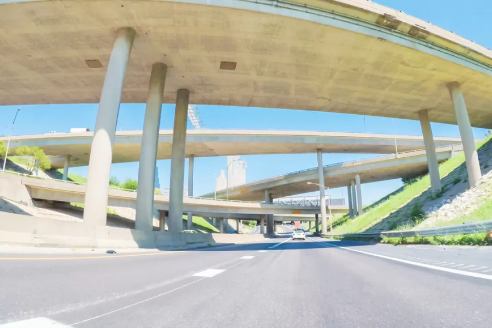 An image taken from the point of view of a driver on a mostly empty freeway, with large overpasses overhead.